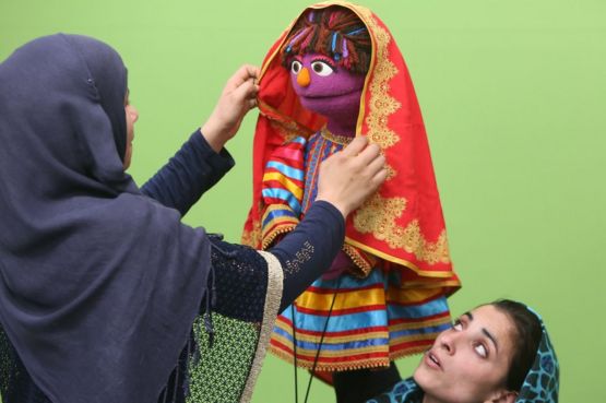 An Afghan puppeteer adjusts a scarf on Zari