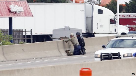 A sniper and a tactical officer take up positions on the shoulder of Interstate 45 at Dowdy Ferry Road during a stand off with a gunman barricaded inside a van at a Jack in the Box, Hutchins, Texas, 13 June 2015