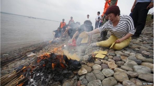 Family members of the Eastern Star cruise ship victims burn joss paper as they mourn.