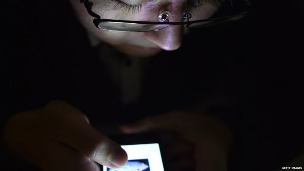 A man in the dark looking at his phone