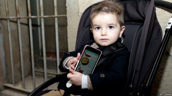 A child in a pram with a smartphone