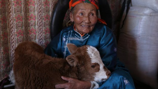 Older woman with an animal, inside a home