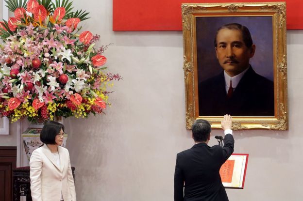 Taiwan's President Tsai Ing-wen (left), standing next to a huge flower display, looks on as Chen Chien-jen swears-in as vice president, holding his right hand up in open-palmed salute, in front of a painting, in Taipei on 20 May 2016