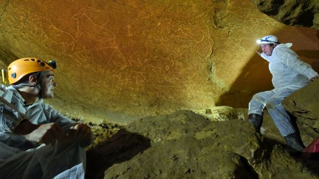 the Cultural Heritage Service Manager of the Provincial Council of Biscay, Andoni Iturbe (L) and professor of Prehistory Cesar Gonzalez (R) looking at cave engravings representing animals like horses, bisons, lions or goats, in the Armintxe cave in the Basque village of Lekeitio