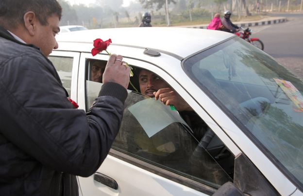 Indian civil defence volunteers distribute roses and urge commuters to stick to the rules