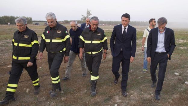 Mr Renzi walking alongside members of the emergency services, 12 July 2016