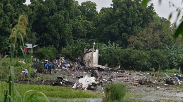 People gather at the site where a cargo plane crashed into a small farming community on a small island in the White Nile river