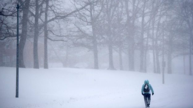 A pedestrian walks through snow in Parkville, Md., Saturday, Jan. 23, 2016.