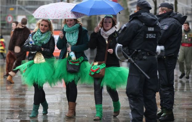 Carnival enthusiasts walk past members of the German police in Cologne