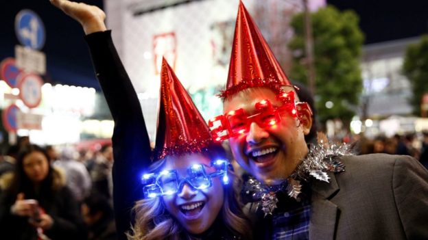 Revellers wearing glasses in the shape of 2017 pose during a new year countdown event at Shibuya crossing in Tokyo, Japan, December 31, 2016