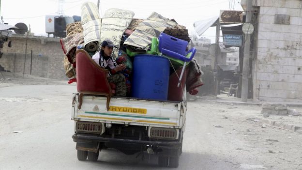 A man sits on the back of a pick-up truck with belongings of his home as he flees Kafr Hamra village in northern Aleppo countryside, Syria (February 27, 2016)