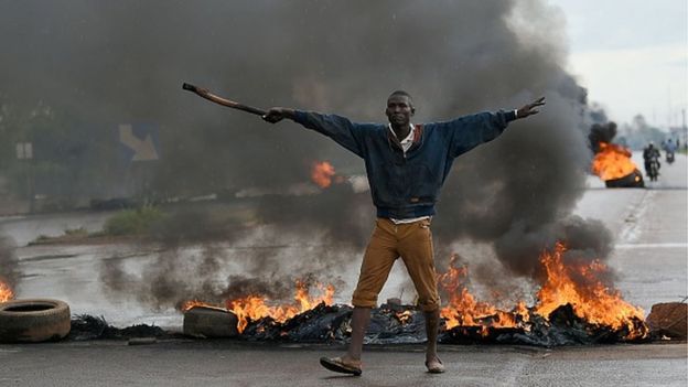 A man gestures as he stands in front of burning tyres on 19 September 2015 in Ouagadougou, Burkina Faso's capital.