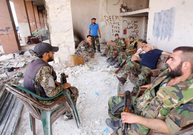 Syrian army soldiers gather at the entrance of a damaged building in the government-controlled part of the besieged town of Darayya, 26 August 2016