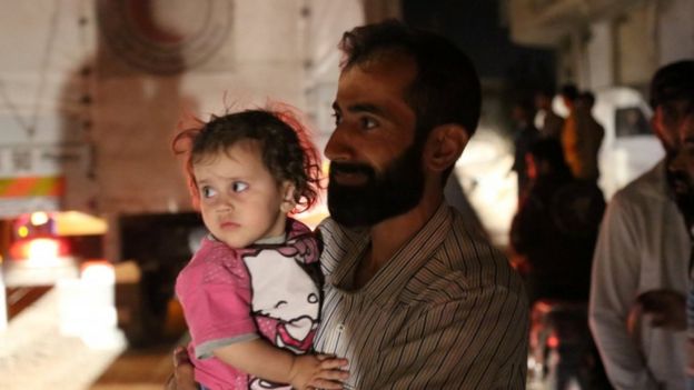 A man holds a child as supplies arrive in Daraya