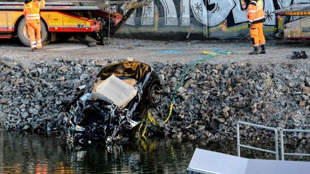 A badly damaged car is towed up from the canal under the E4 highway bridge in Sodertalje, Sweden
