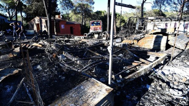 Firefighters inspect the damage after a wildfire swept over a campsite in Bagnols-en-Foret