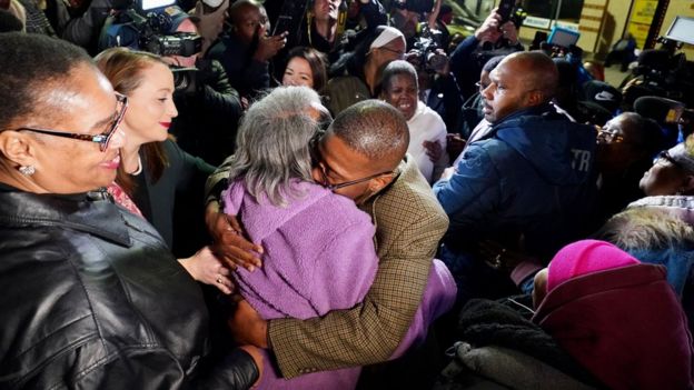 Alfred chestnut hugs his mother surrounded by a crowd