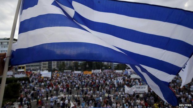 A protester waves a Greek flag during an anti-austerity pro-government rally in front of the parliament building in Athens, Greece, on 21 June 2015.