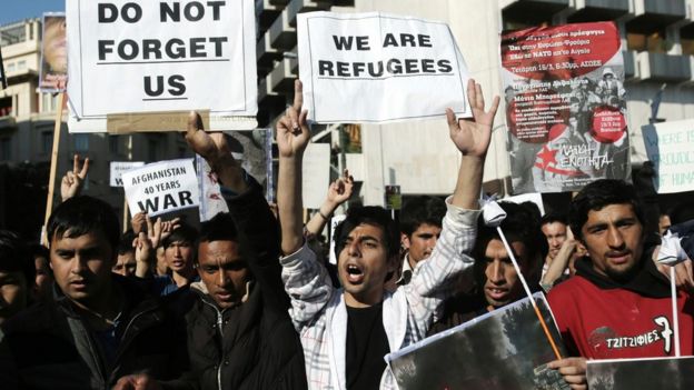 Men shout slogans as they hold banners reading