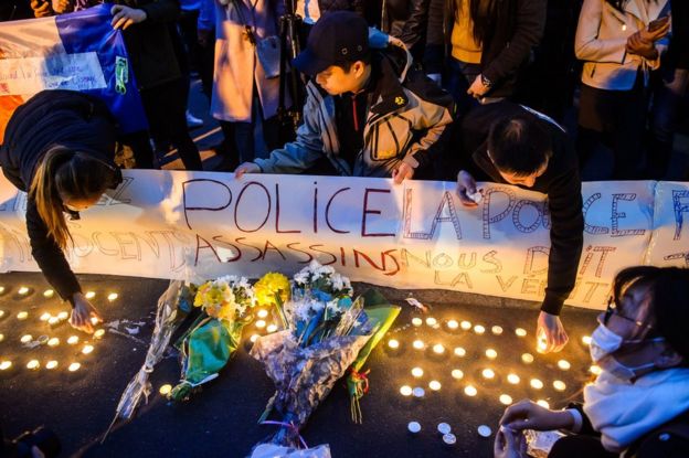 Membersof the French Chinese community gather and light candles outside a police station behind a banner reading 