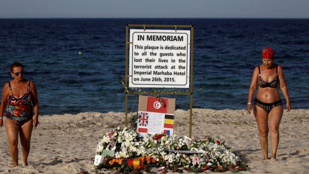 Tourists pass a plaque dedicated to victims on the beach of the Imperial Marhaba resort,