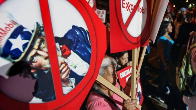 Una manifestante con un cartel contra ExxonMobil