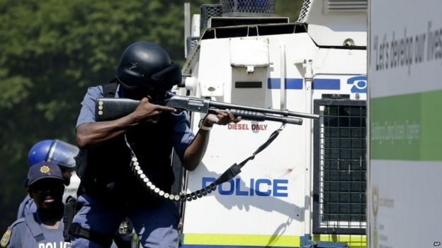 Riot police officer aims at protesters during the march against university tuition hikes outside the union building in Pretoria, South Africa,
