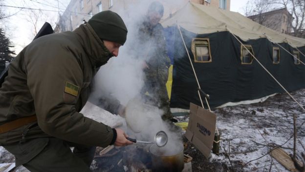 Ukrainian servicemen cook near a tent set to warm local residents of Avdiivka in the Donetsk region after the town's heating was damaged by shells on 31 January 2017.