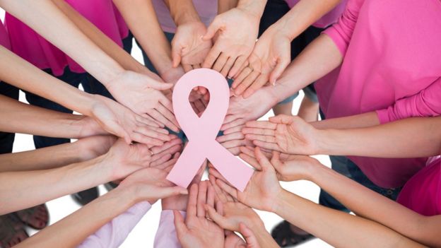 Manos de mujeres con el símbolo de la lucha contra el cáncer.