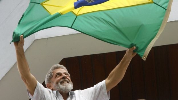 Luiz Inacio Lula da Silva waves a Brazilian flag to supporters f-rom the balcony of his apartment
