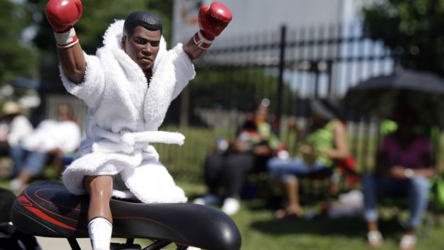 Muhammad Ali action figure sits on seat of bicycle - 10 June