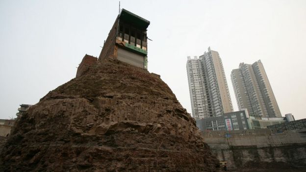 Chongquing, China, 21 March 2007. A house, whose owner refused to accept a compensation deal by a property developer, is surrounded by excavated land at a construction site.