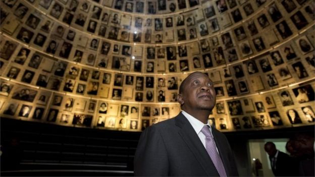 Uhuru Kenyatta, looks up and around at the photographs in the conical shaped 