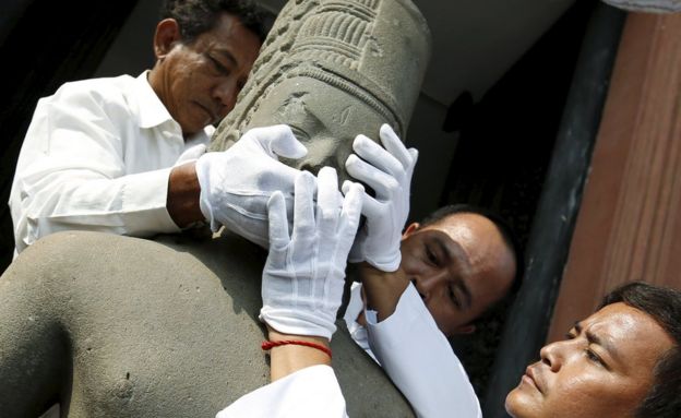 The head belonging to the Harihara statue is reattached to its body by museum employees during a ceremony at Cambodia