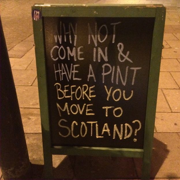 Letrero de pub con la frase ¿Por qué no entras y te tomas una cerveza antes de que te mudes a Escocia?