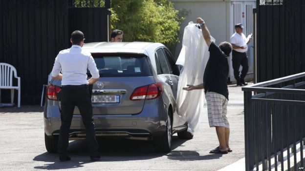 A man holds clothes on a hanger as he arrives at the villa of the Saudi king in Vallauris