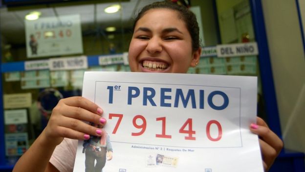 Winner Imanes Naamane celebrates as she holds a placard showing the first prize winning number, 79140, of Spain's Christmas Lottery 