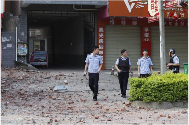 Police investigators inspect the area around a damaged building a day after a series of blasts in Liucheng county in Liuzhou, south China