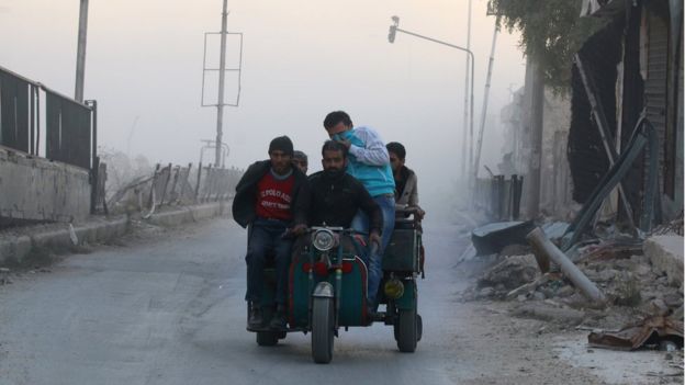 Men ride on a vehicle amidst dust after a strike on the rebel held besieged al-Shaar neighbourhood of Aleppo, Syria