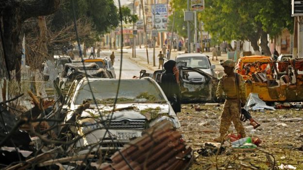 A woman stands next to a military on the scene of a terror attack on the Ambassador Hotel claimed by Somalia
