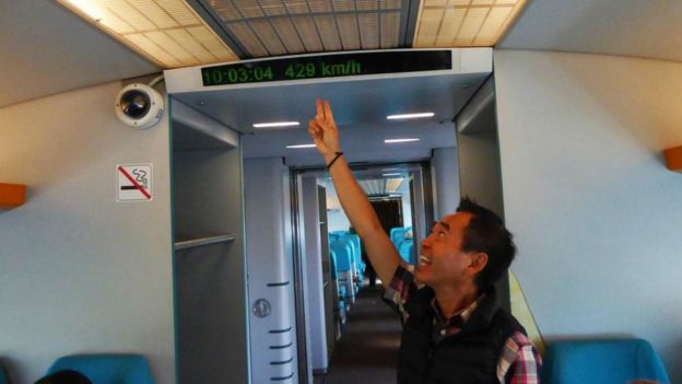 Un pasajero señalando un generador de caracteres dentro del tren que muestra a qué velocidad viaja