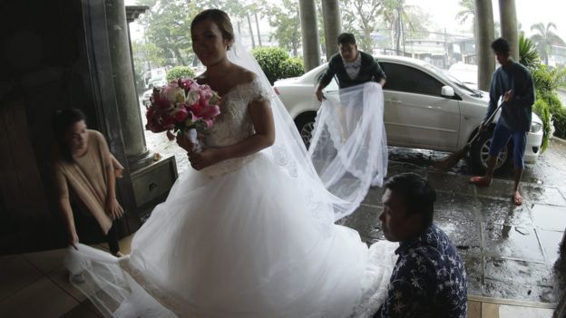 A bride arrives for her wedding in the Philippines despite the onset of Typhoon Koppu