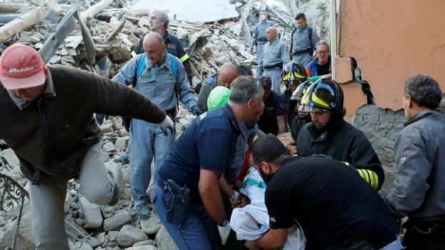 Rescuers carry a person on a stretcher following the quake in Amatrice,, Italy (24 August 2016)