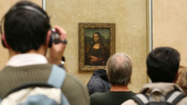 Visitors stand at the Mona Lisa in The Louvre in Paris