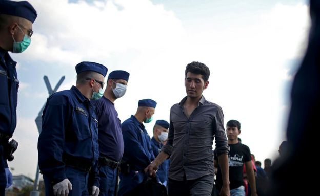 Migrants are escorted by Hungarian police officers as they wait to board a bus at a migrant collection point near the Serbian Hungarian border in Roszke, Hungary September 13, 2015.