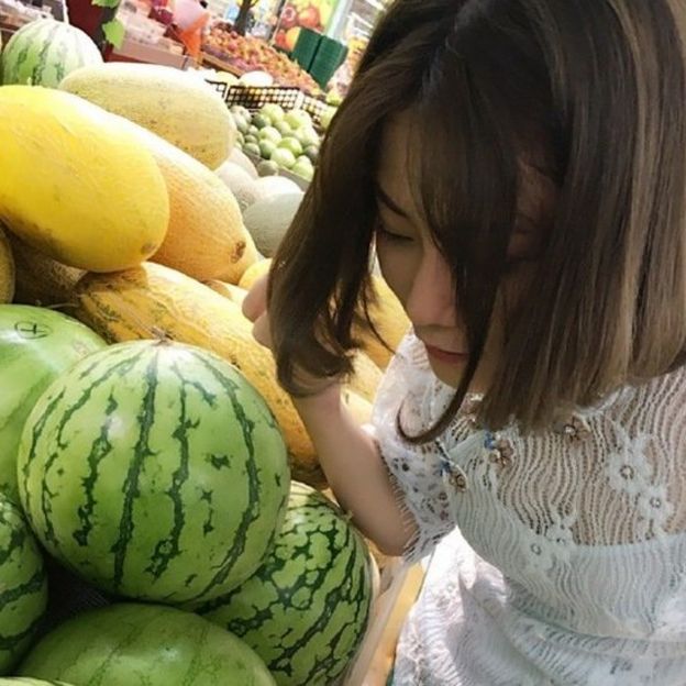 Photo of a woman knocking on a watermelon