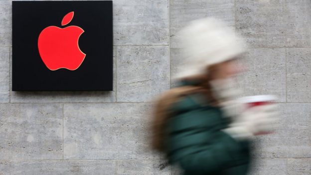 Una chica pasa una tienda de Apple con el logo en rojo por la campaña del World Aids Day (foto de diciembre).