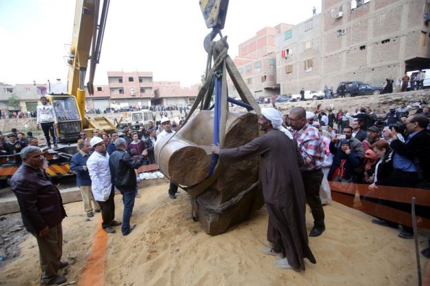 Egyptians look on as a crane lifts parts of a statue for restoration after it was unearthed at Souq al-Khamis district, at al-Matareya area, Cairo, Egypt, 13 March 2017