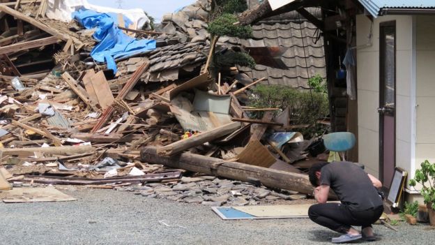 A man in front of a collapsed residence where his mother is trapped after an earthquake in Mashiki, Kumamoto prefecture, southern Japan (16 April 2016)