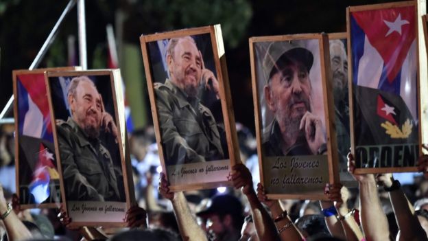 Personas sosteniendo cuadros con fotos de Fidel Castro.